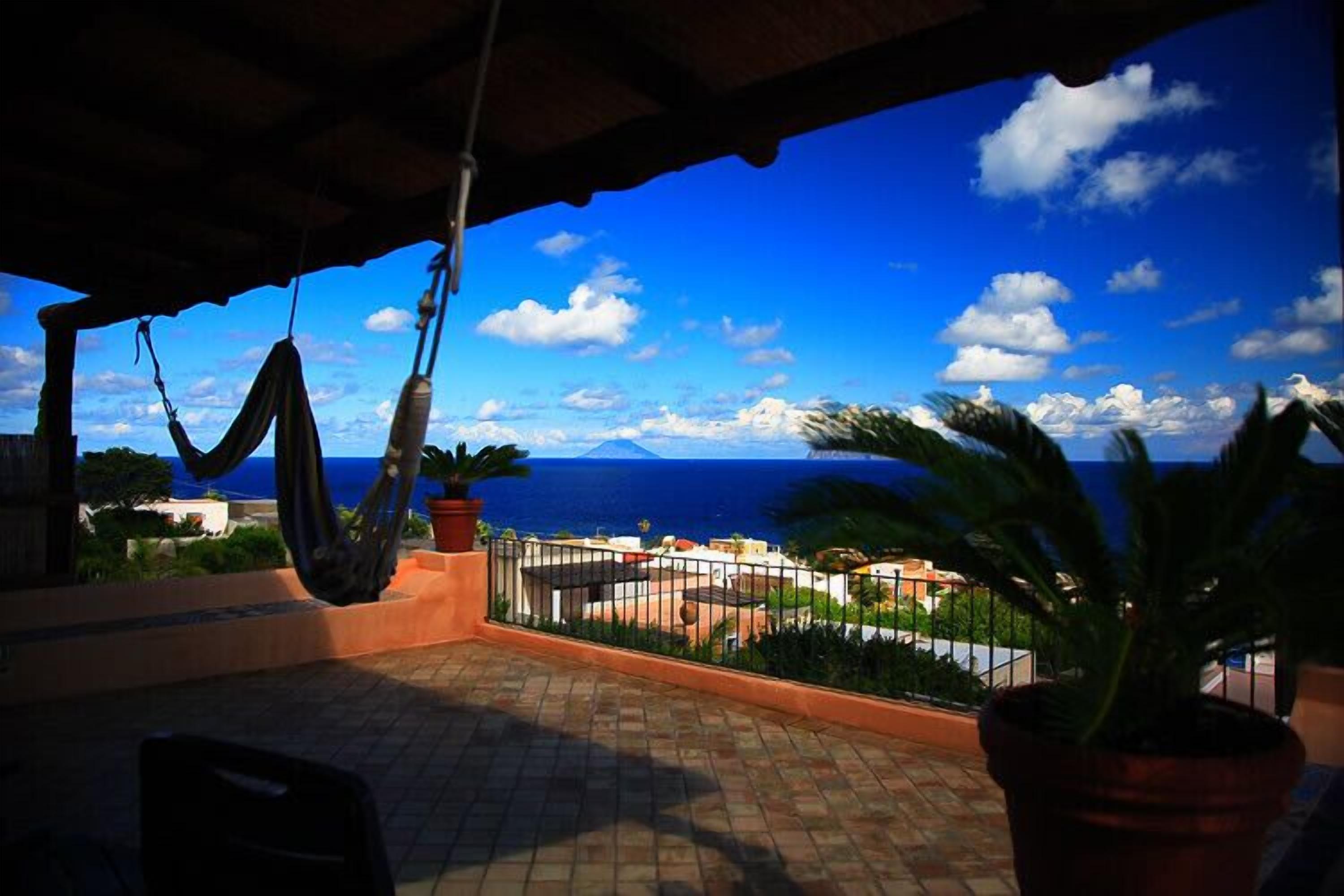 Un balcón con vista al mar y una hamaca.