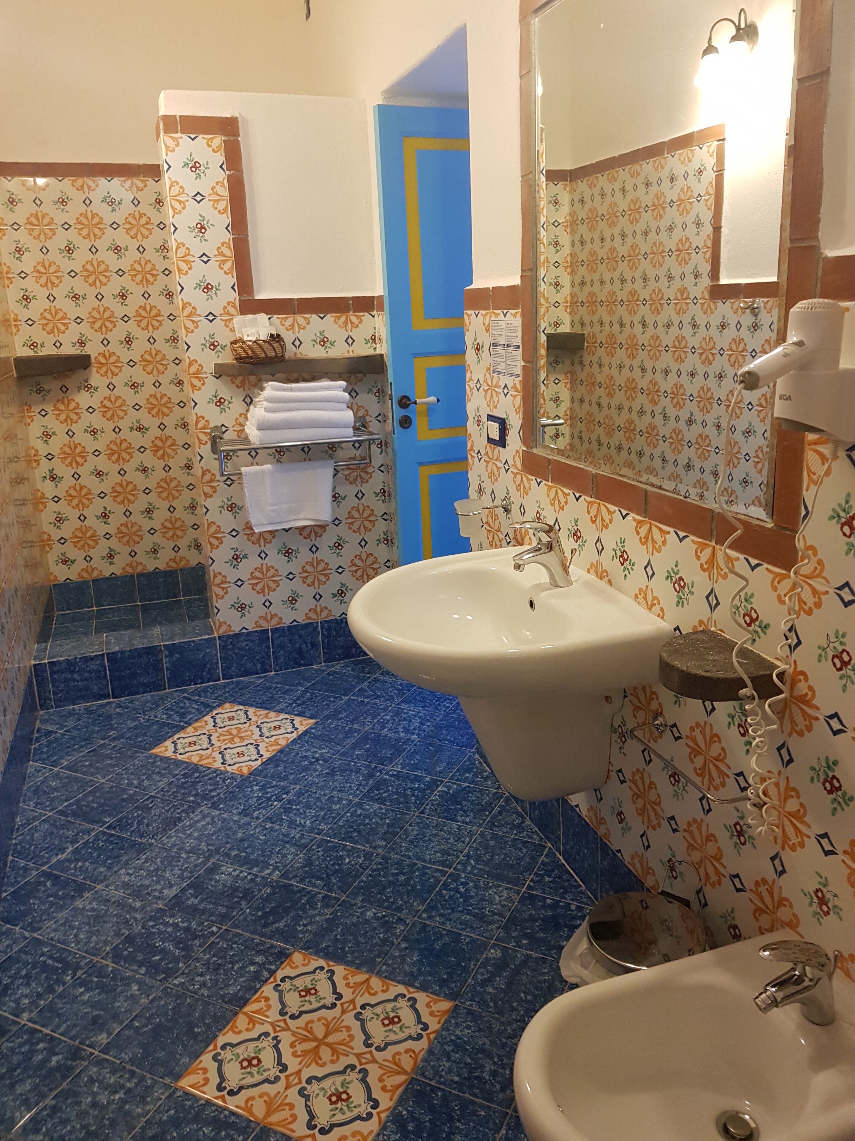Een badkamer met patroon betegelde vloertegels, een wastafel, een spiegel en een handdoekrek.
