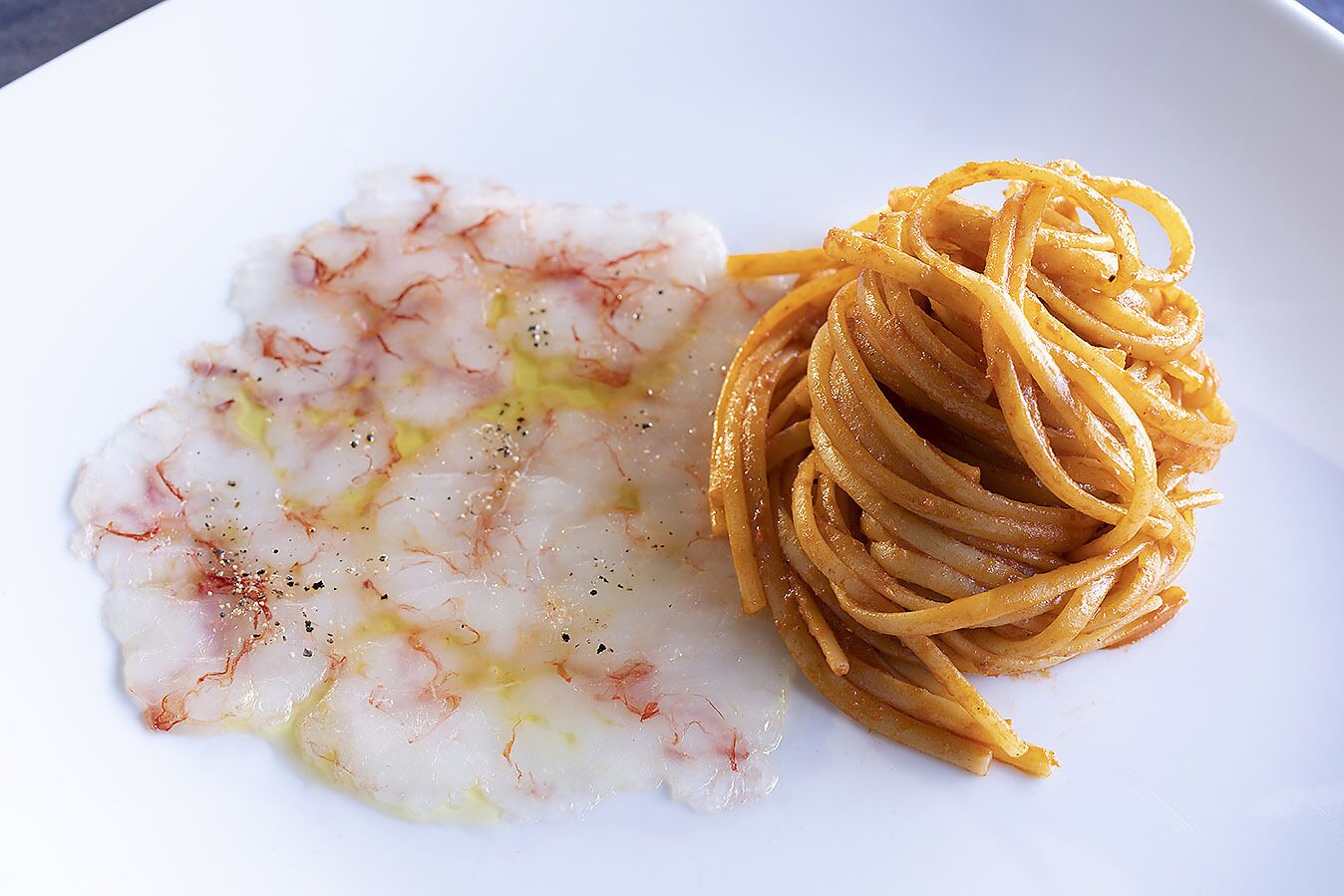 A plate with a seafood dish and a stack of pasta.