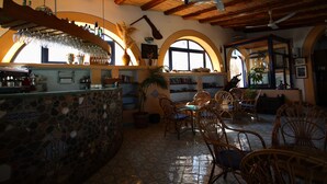 Un restaurante con mostrador de piedra, sillas de mimbre y techo de madera.