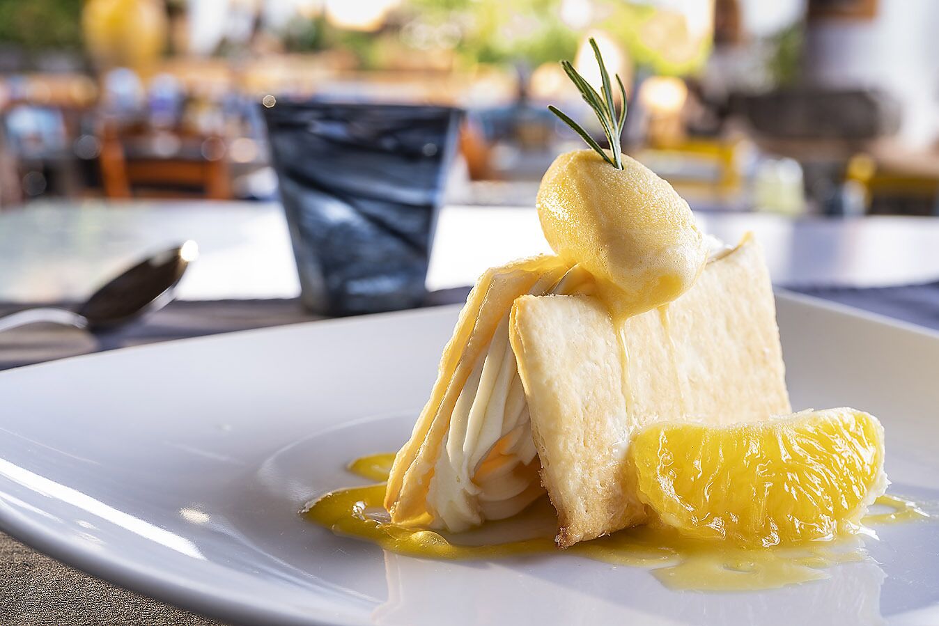 A dessert on a white plate with a sprig of rosemary on top.