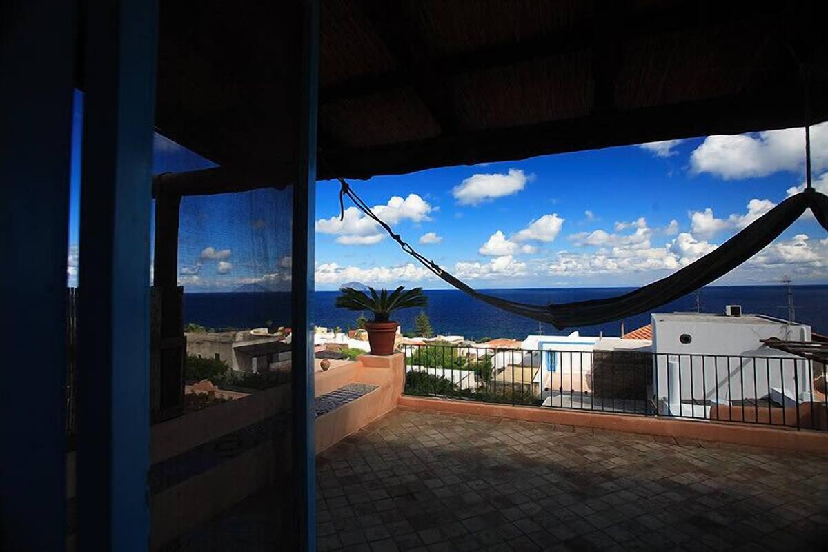 Un balcón con vista al mar y una hamaca.