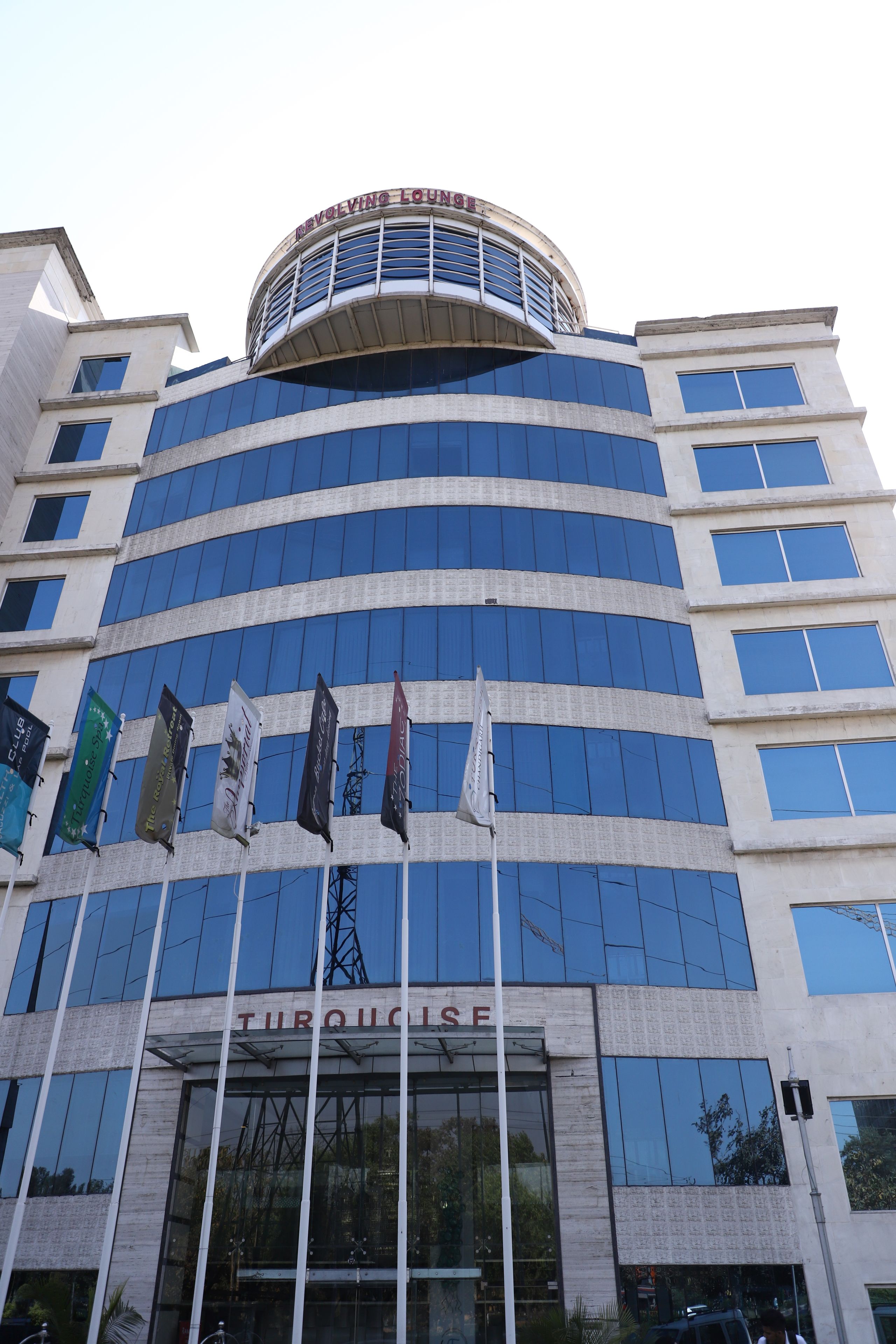 A modern building with a curved facade, multiple windows, and flags.