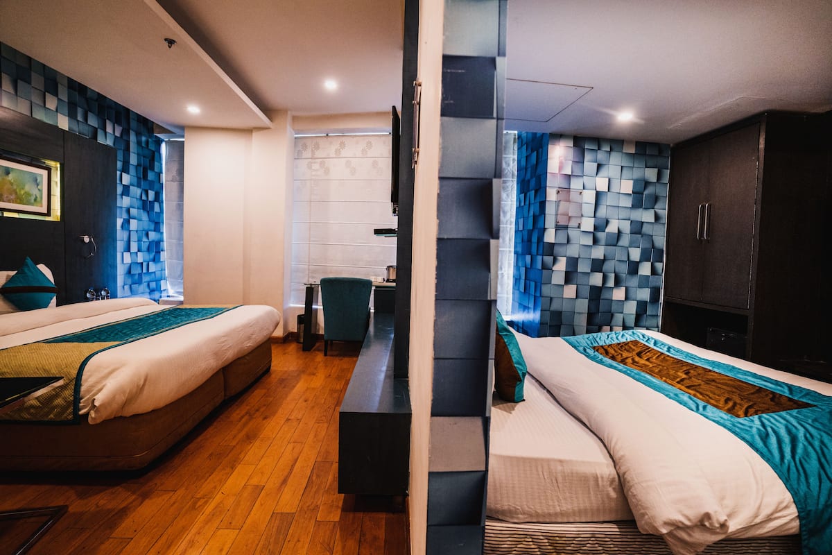 Ein modernes Hotelzimmer mit zwei Betten, einem Schreibtisch und Blick auf die Stadt.