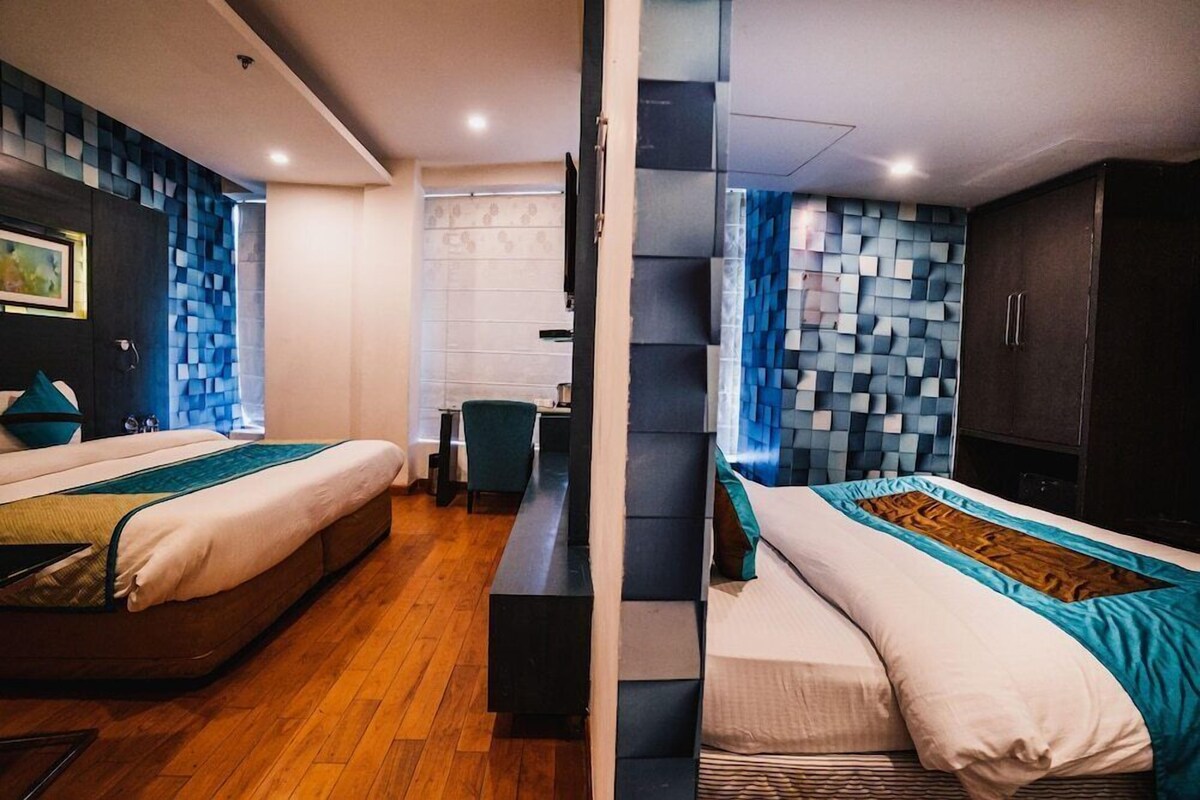 Et moderne hotelværelse med to senge, et skrivebord og udsigt over byen.