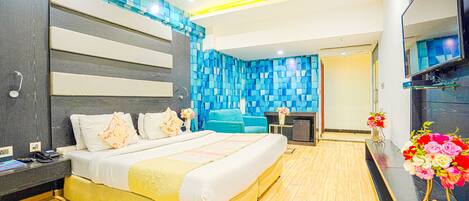 Een moderne slaapkamer met een groot bed, een televisie en een decoratieve vaas met bloemen.