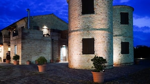 A brick building with a cylindrical tower, potted plants, and a paved entrance.