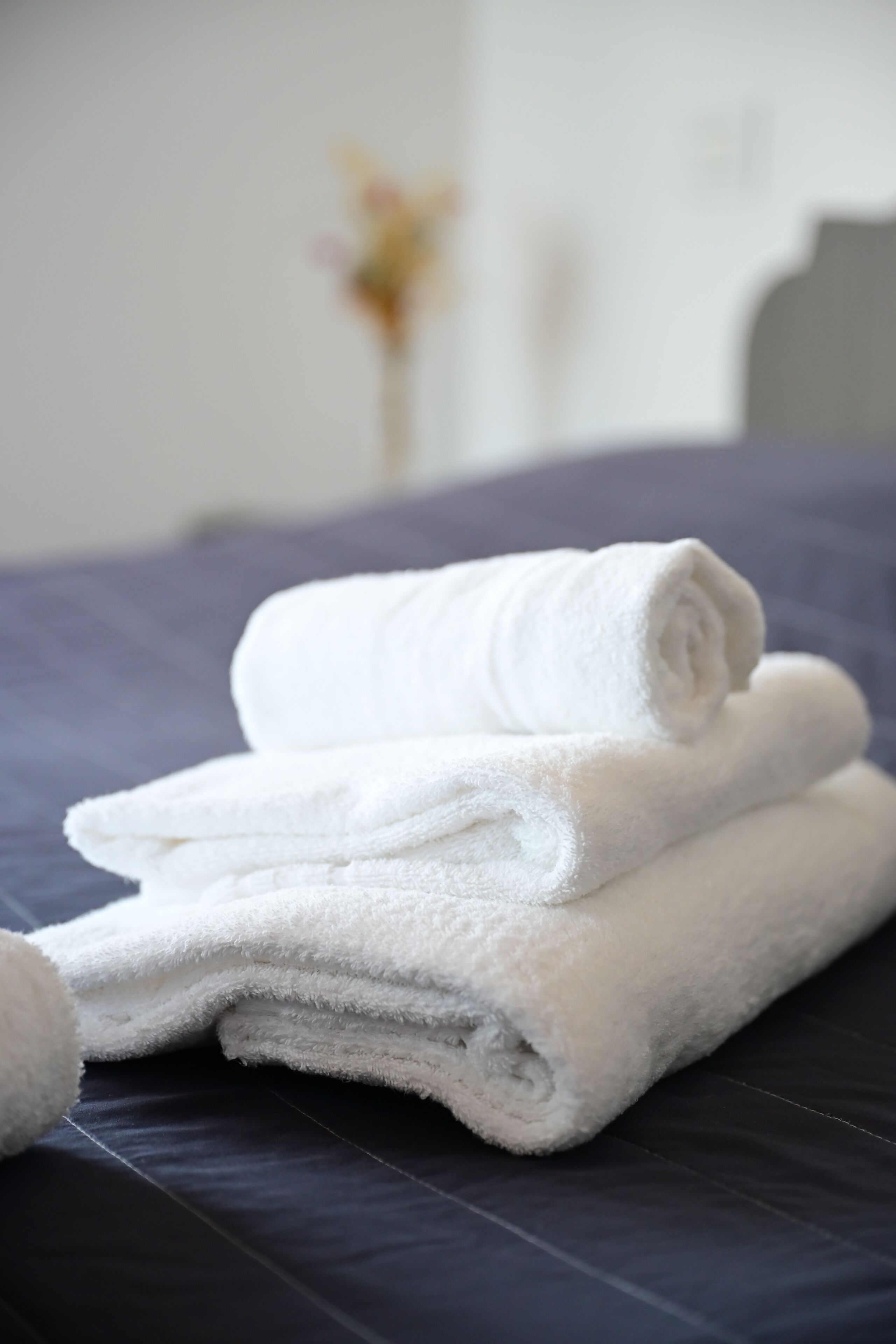 A neatly folded white towel on a dark blue bedspread.