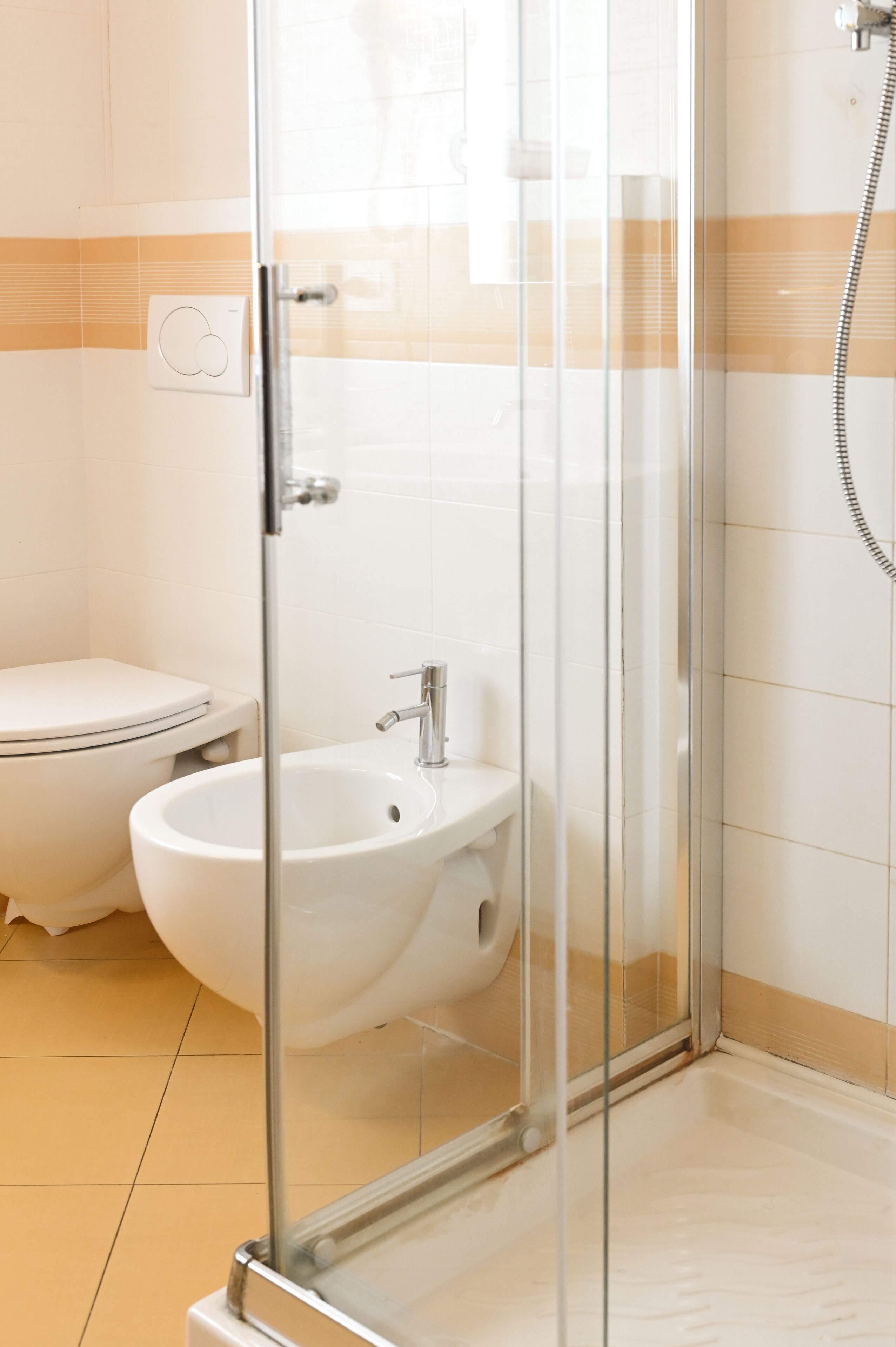 Un baño moderno con cabina de ducha de vidrio, un lavabo blanco y un inodoro.