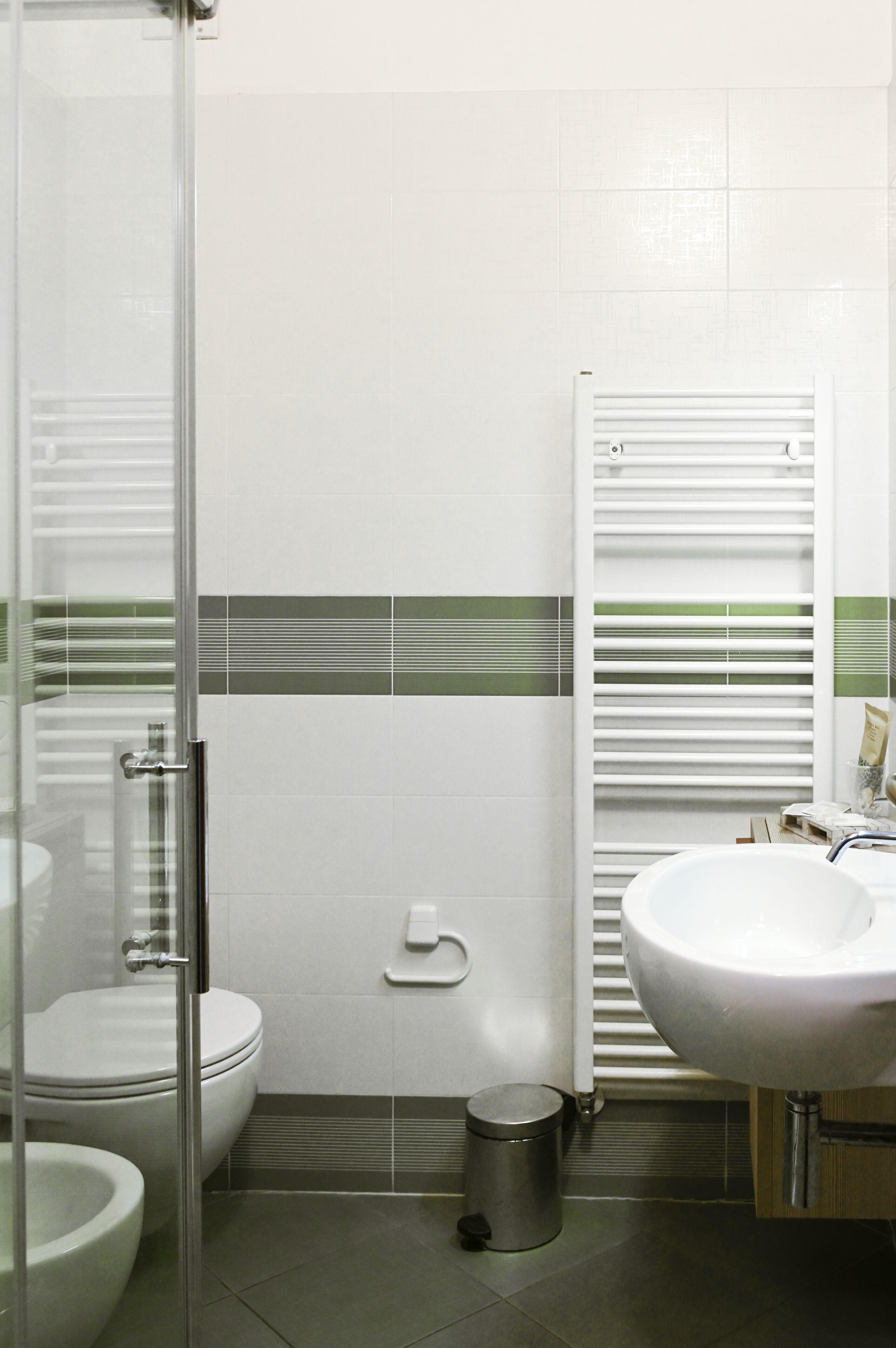 Une salle de bain comprenant des toilettes, un bidet, un lavabo et une douche à parois de verre.