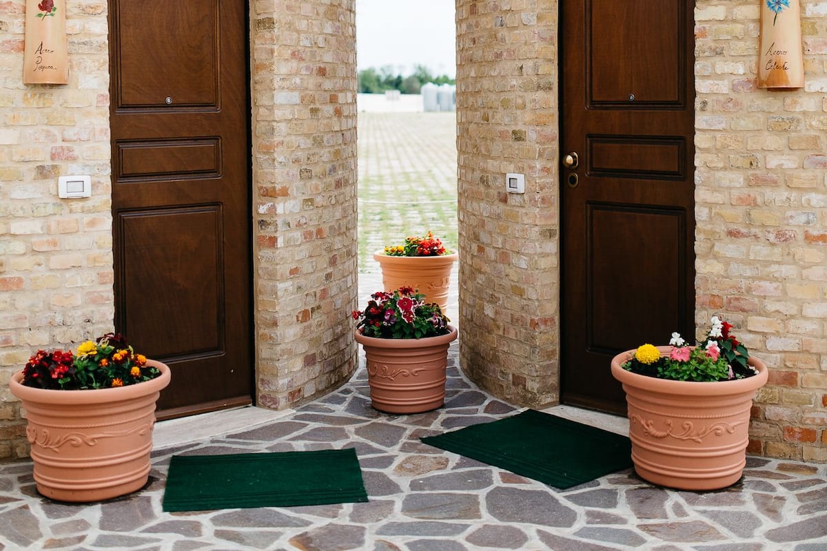 A courtyard with two brick towers, each with a wooden door and potted plants.