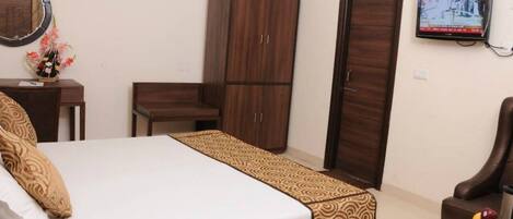 A bedroom with a bed, a wardrobe, a desk, a chair, and a television.