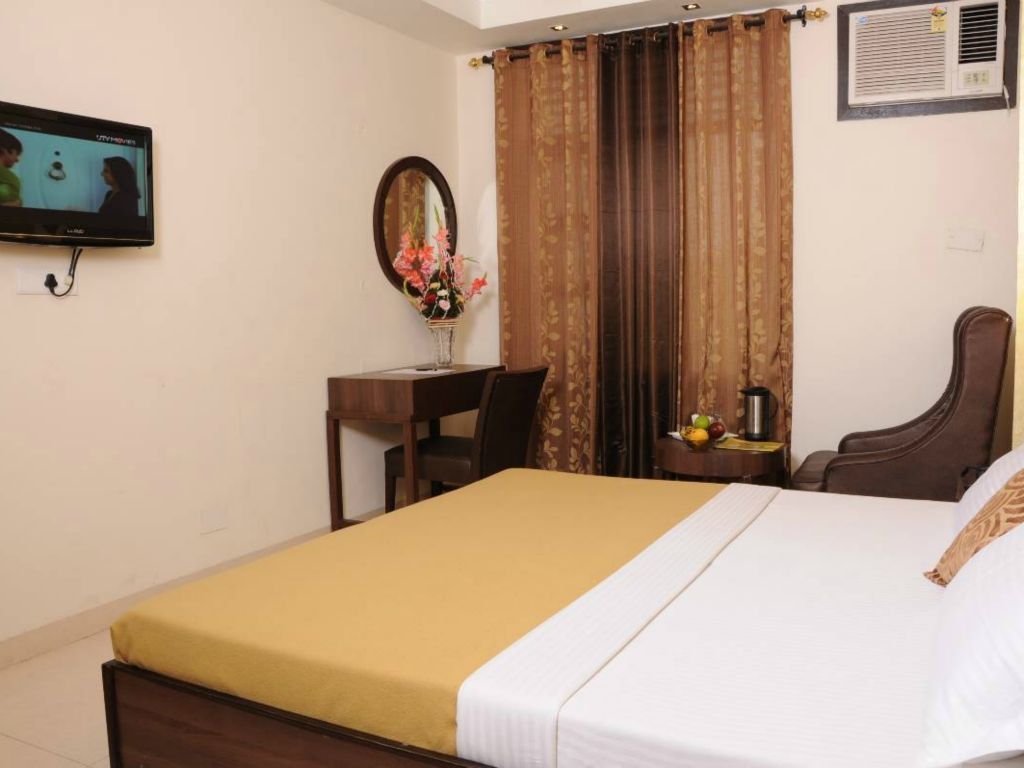 Una habitación de hotel con una cama, un escritorio, una silla, un televisor y un espejo.
