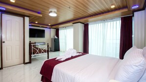 A hotel room with a large bed, a television, a desk, and a wardrobe. - Diamond Water Edge Resort (Boracay Island)