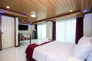 Una habitación de hotel con una cama grande, televisor, escritorio y armario.
