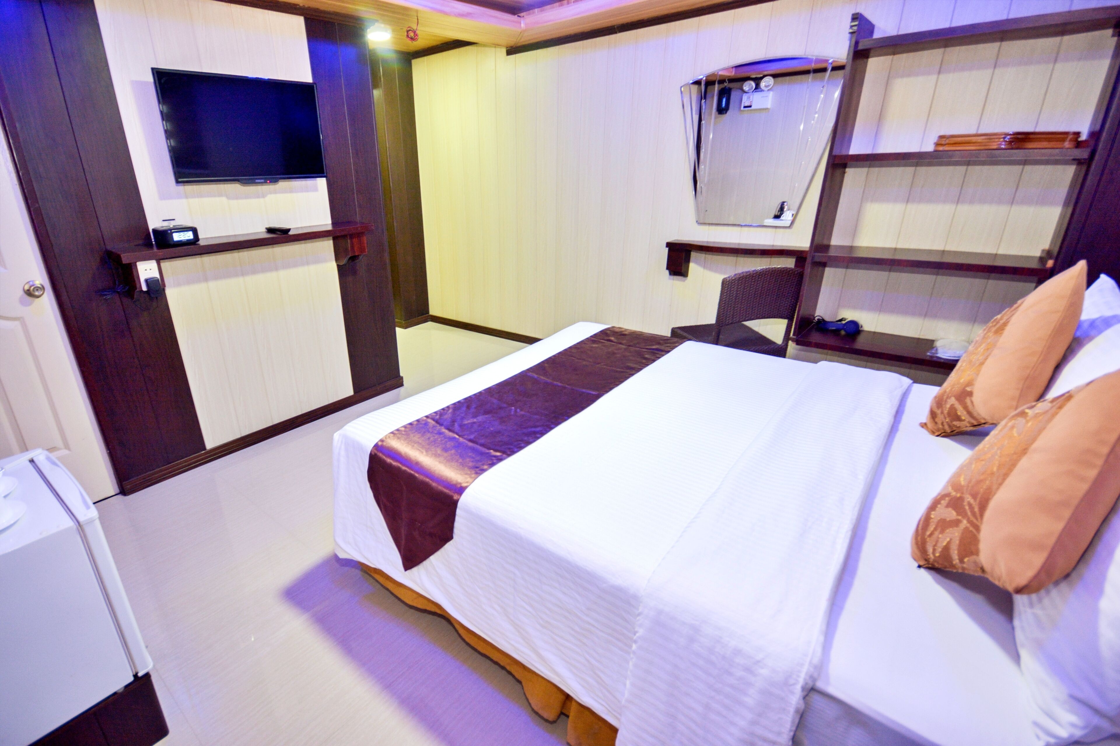 A hotel room with a bed, a television, a desk, and a mirror.