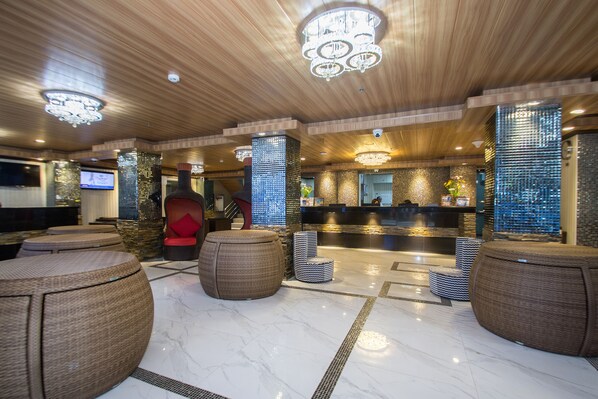 Un hall con mostrador de recepción, asientos de mimbre y techo de madera.