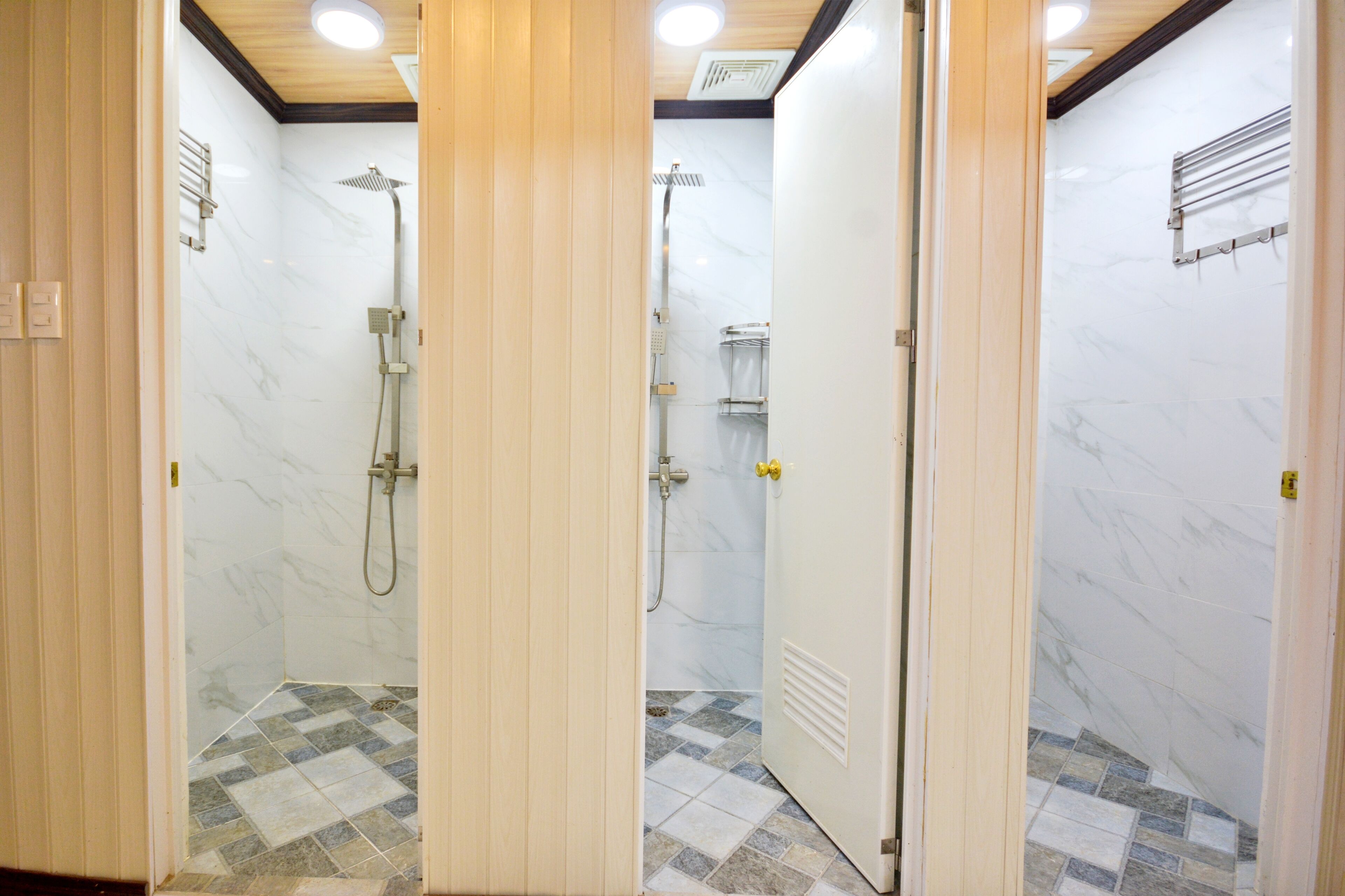 A bathroom with a shower, tiled floor, and wooden paneling.