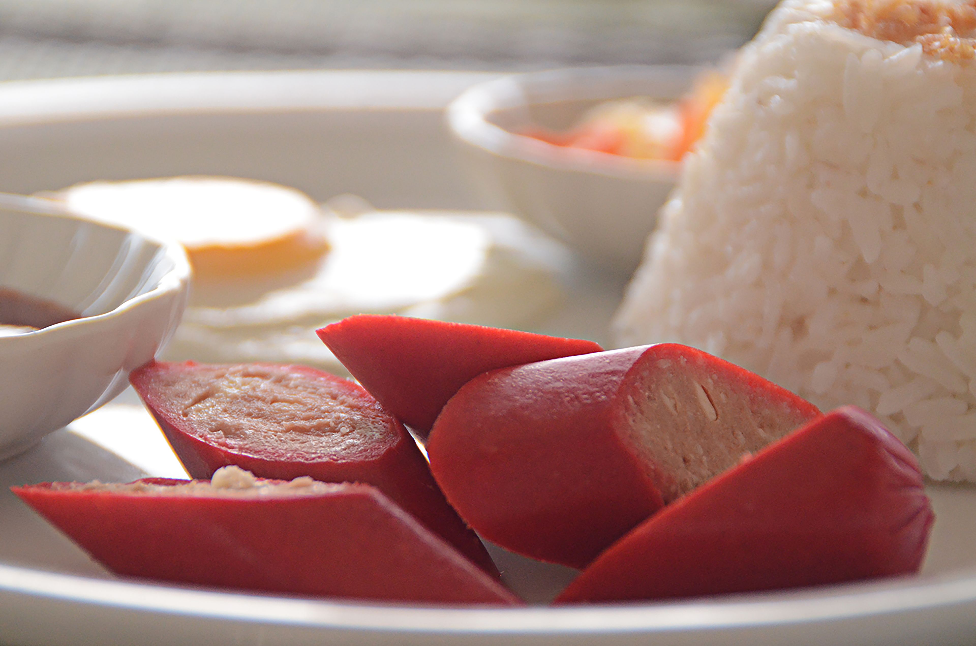 A plate with sliced red meat, white rice, and a small bowl of sauce.
