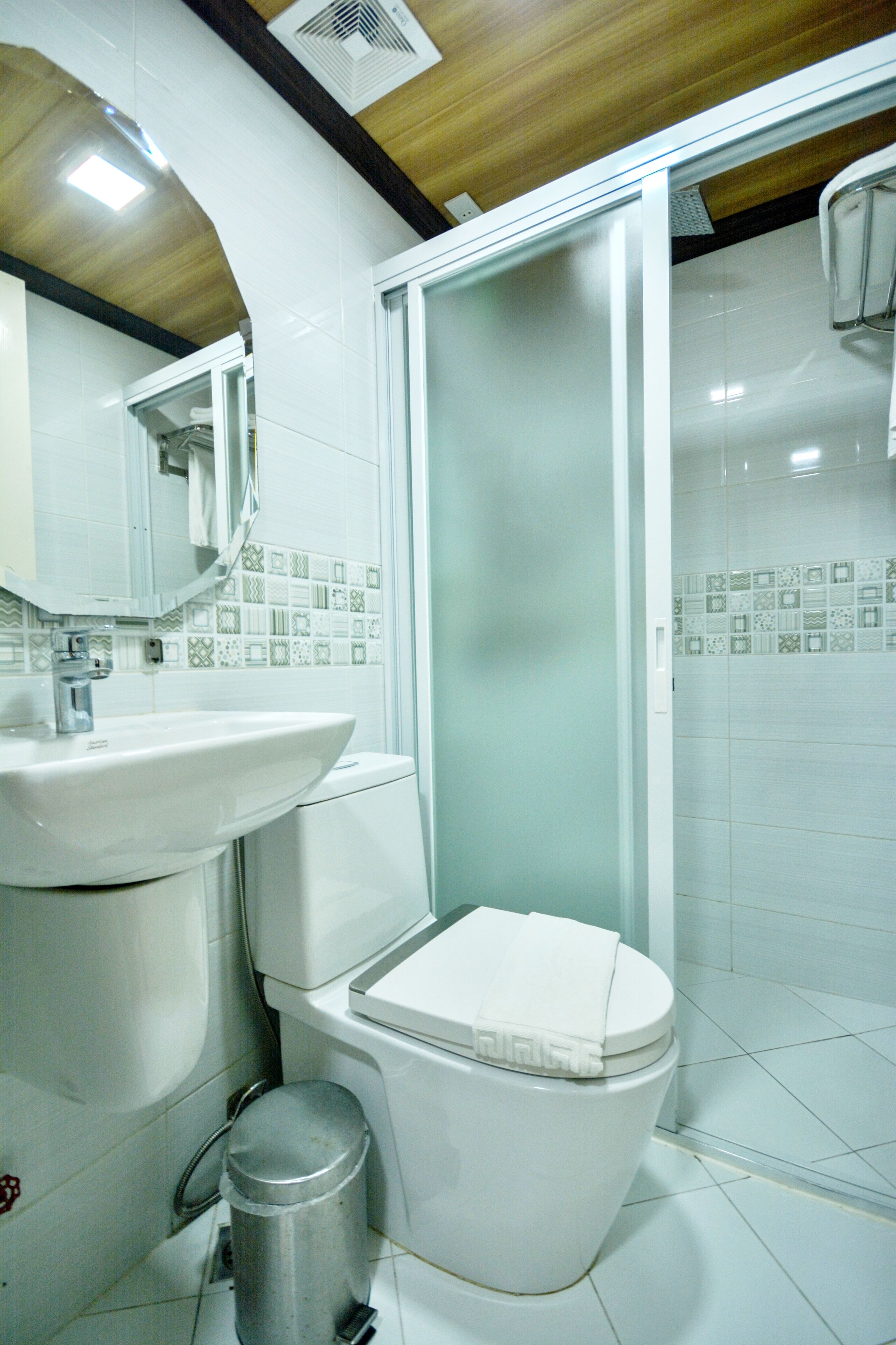 Une salle de bain avec un lavabo blanc, des toilettes et un espace douche.