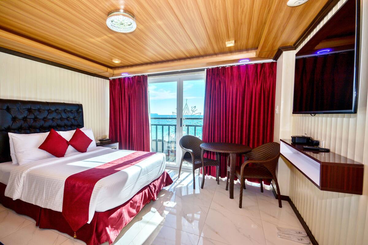 A hotel room with a bed, a desk, a chair, and a TV.