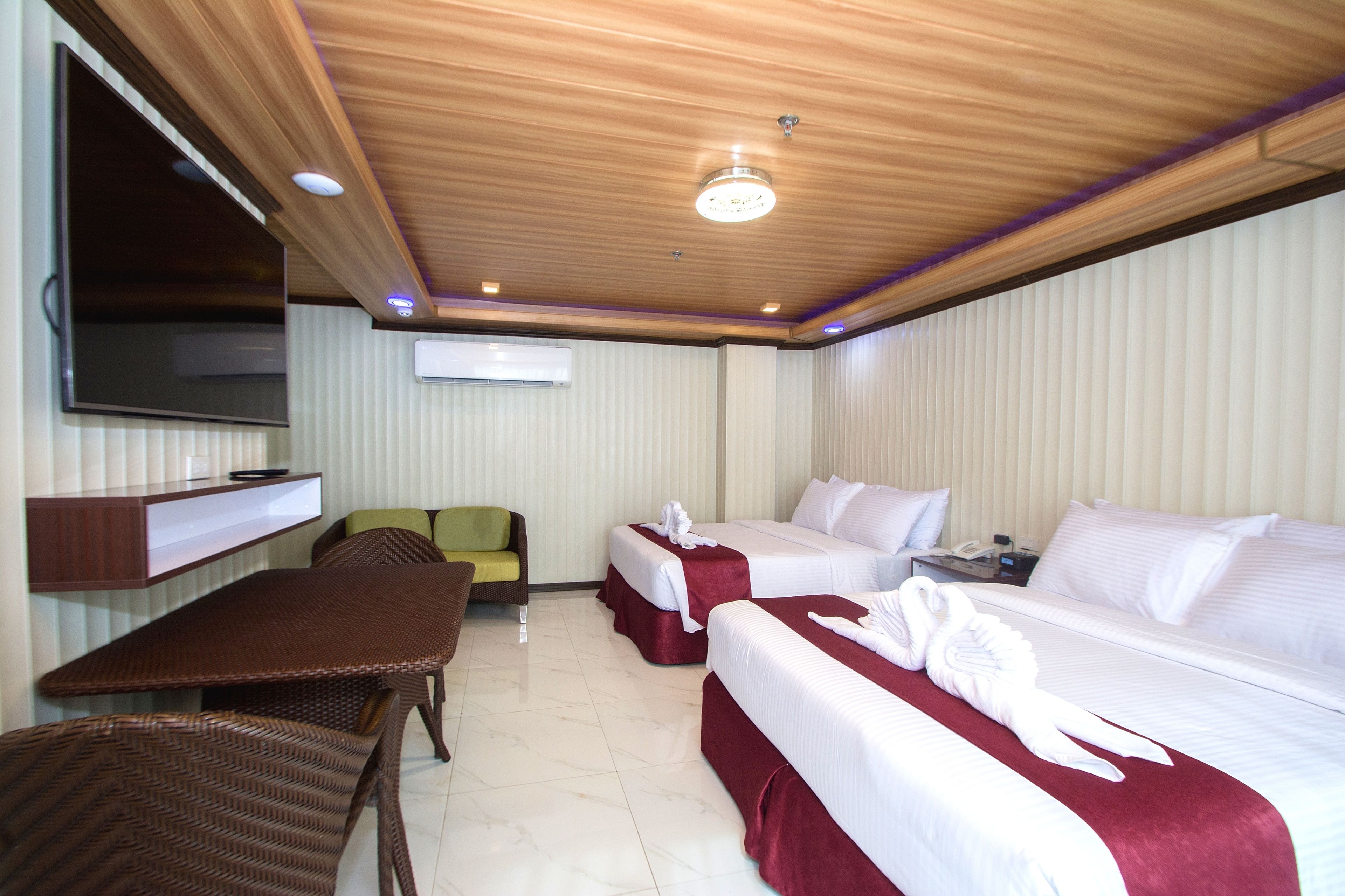 A hotel room with two beds, a TV, a desk, and a chair.