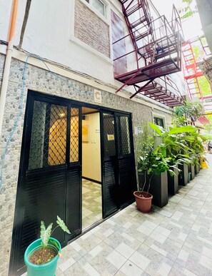 A building with a closed entrance, a fire escape, and potted plants along the pathway. - Diamond Water Edge Resort (Boracay Island)