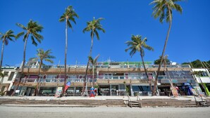 A beachfront hotel with multiple floors, palm trees, and a clear blue sky. - Diamond Water Edge Resort (Boracay Island)