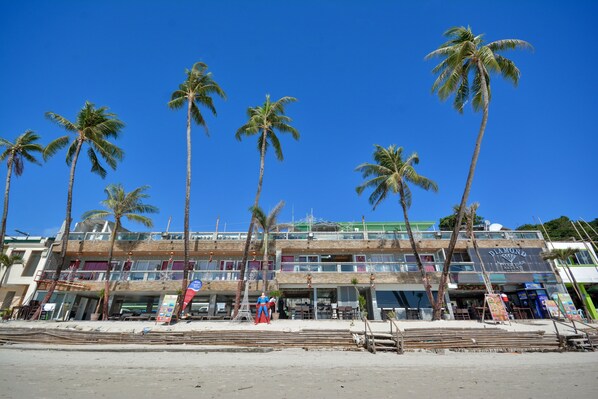 A beachfront hotel with multiple floors, palm trees, and a clear blue sky. - Diamond Water Edge Resort (Boracay Island)