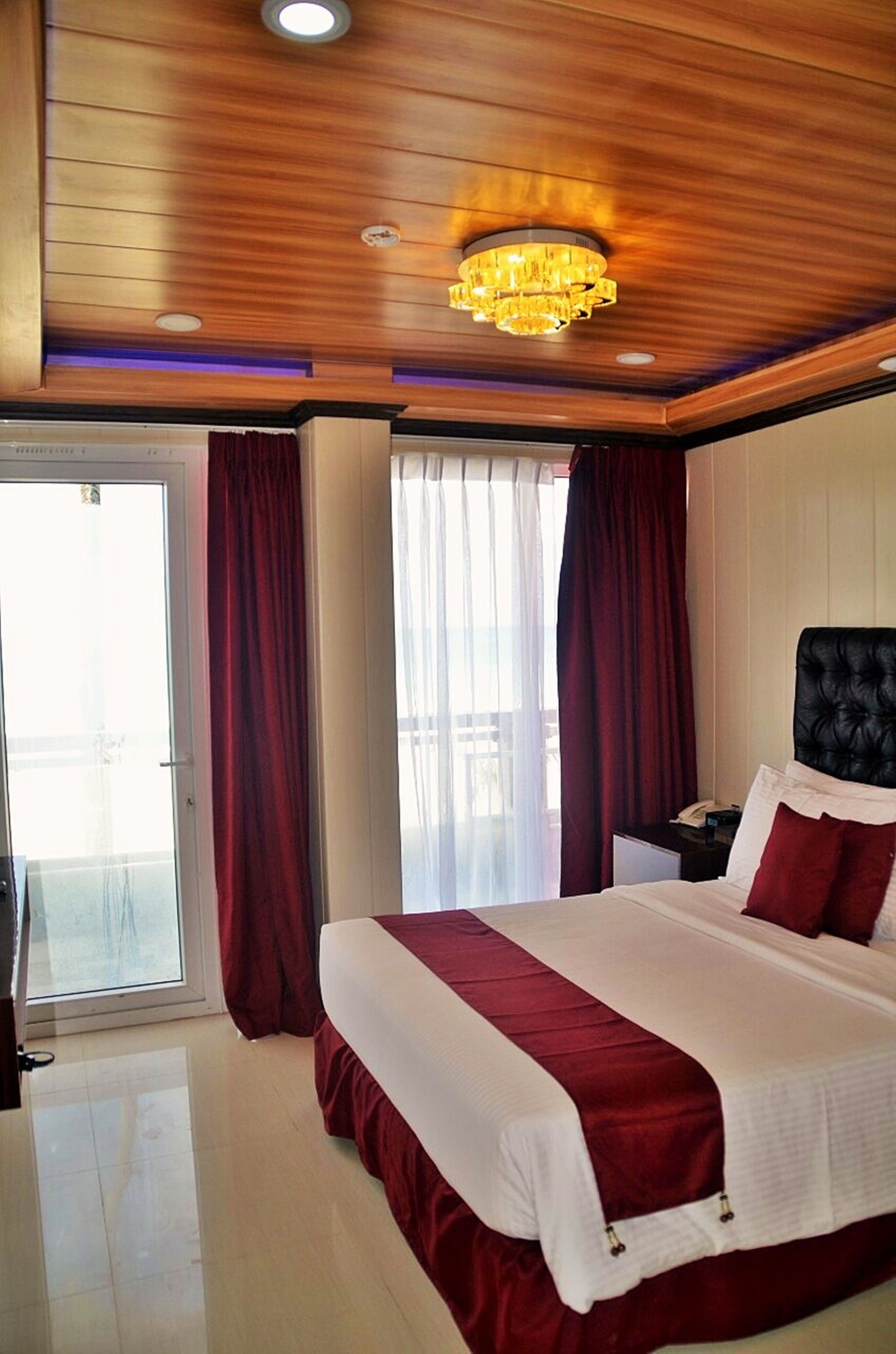 Une chambre d’hôtel avec un grand lit, un plafond en bois et un lustre.