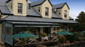 A two-story building with a covered patio area, outdoor seating, and potted plants. - Knysna Wayside Inn (Knysna)