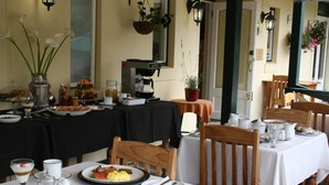 A restaurant with tables set for breakfast, including plates of eggs, bacon, and toast. - Knysna Wayside Inn (Knysna)