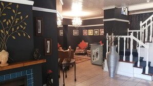 A spacious living area with a fireplace, a staircase, and a dining area. - Knysna Wayside Inn (Knysna)