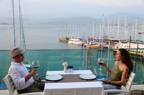 A dining table set for two with a view of the marina and boats in the background. - Alesta Yacht Hotel (Fethiye)