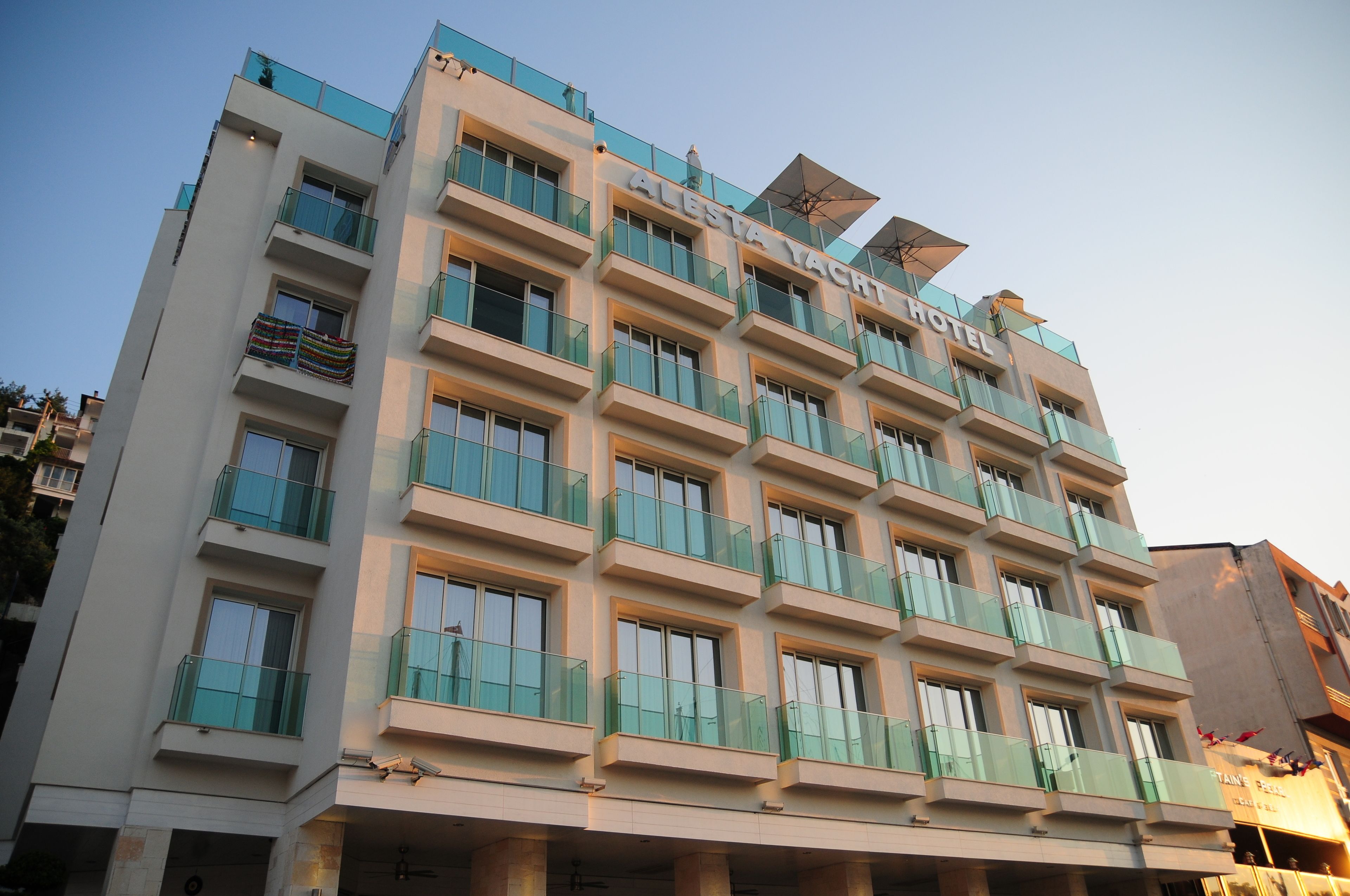 A multi-story hotel with balconies and a sign reading "Alesta Yacht Hotel."