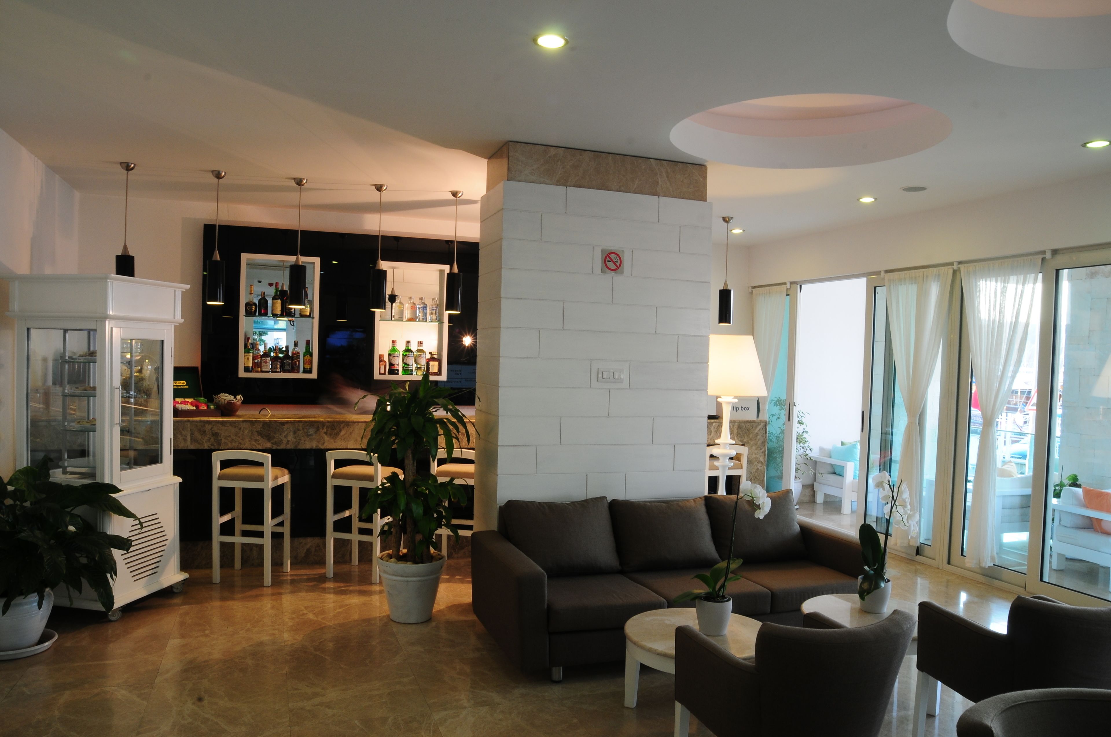A modern hotel lobby with a bar area, seating arrangements, and large windows.