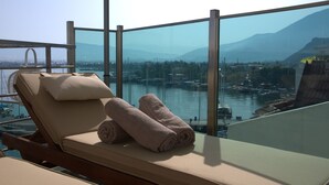 A sunlit balcony with a lounge chair and towels, overlooking a marina and distant mountains. - Alesta Yacht Hotel (Fethiye)