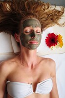 A person lying on a bed with a towel and flowers beside them.