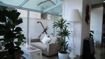 Una sala de estar moderna con techo de vidrio, un sofá, una mesa de centro y plantas en macetas.