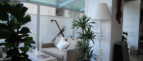 A modern living room with a glass ceiling, a sofa, a coffee table, and potted plants.