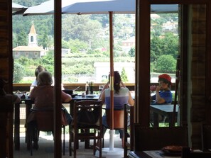 A restaurant with outdoor seating overlooking a town with a church and greenery. - Quintinha D' Arga (Caminha)