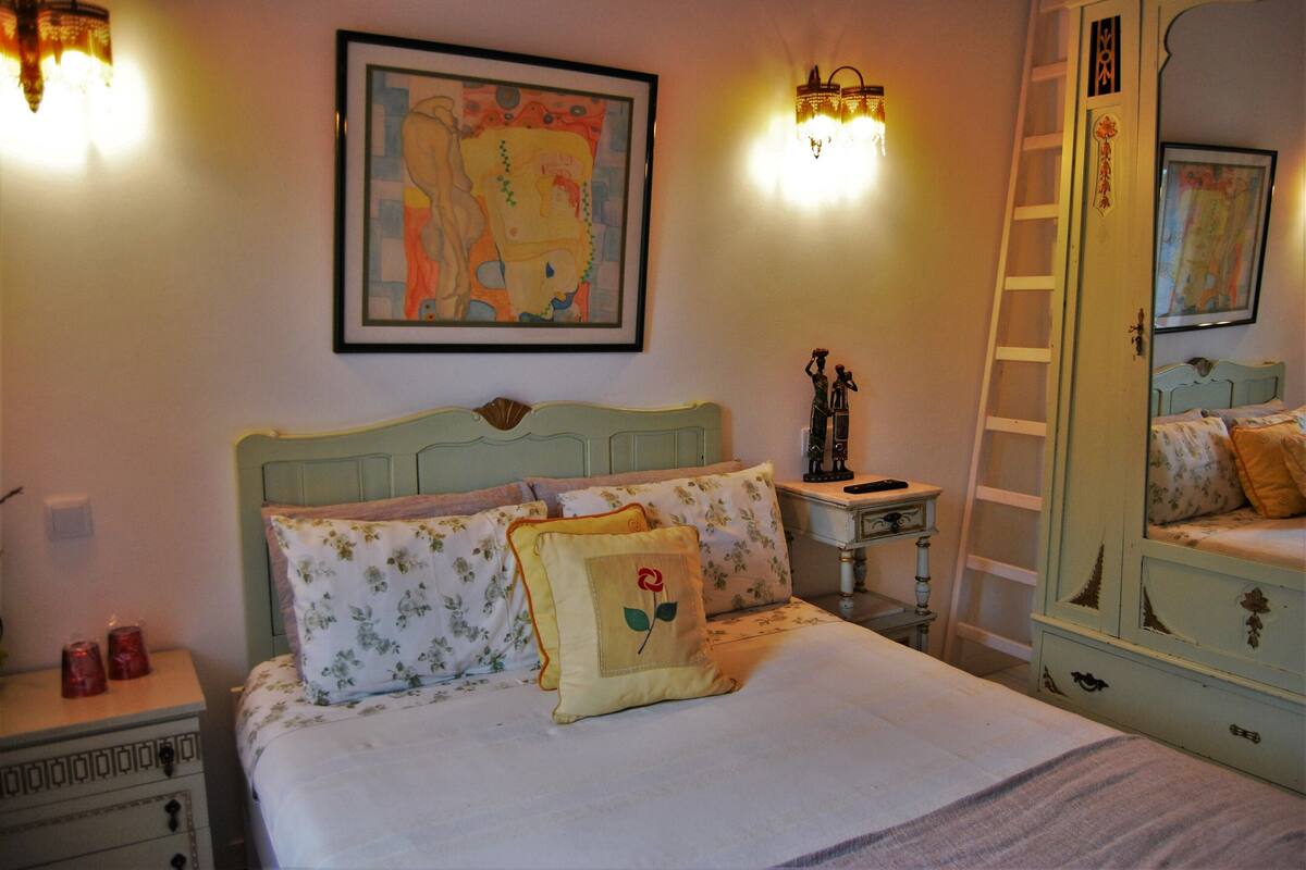 Ein Schlafzimmer mit Bett, Nachttisch, Schminktisch und Wandbildern.