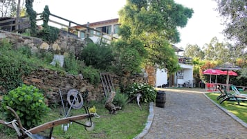 Un camino empedrado que lleva a un edificio con un muro de piedra y una valla de madera.