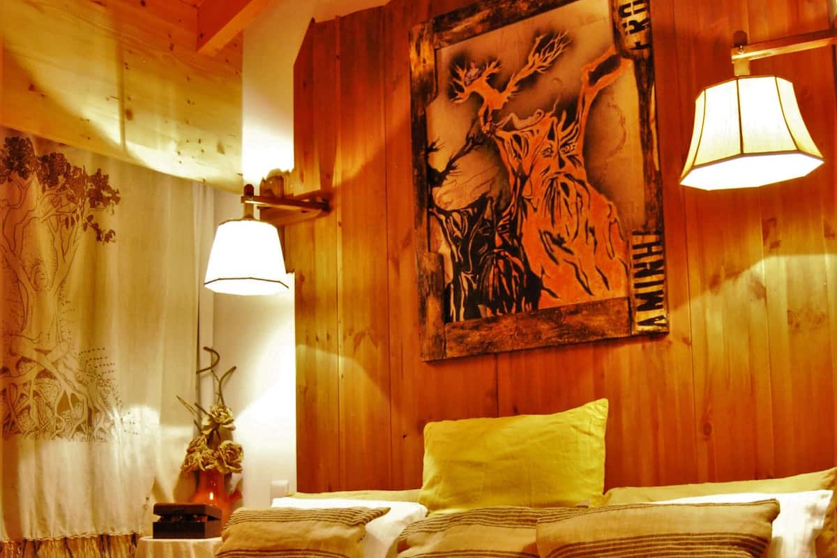 Ein Zimmer mit Holzwänden, einem Bett, einer Lampe und einem an der Wand hängenden Gemälde.