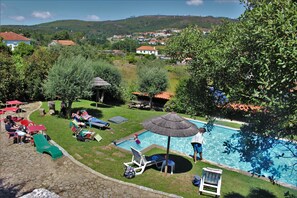 A backyard with a swimming pool, lounge chairs, and a dining area with tables and chairs. - Quintinha D' Arga (Caminha)