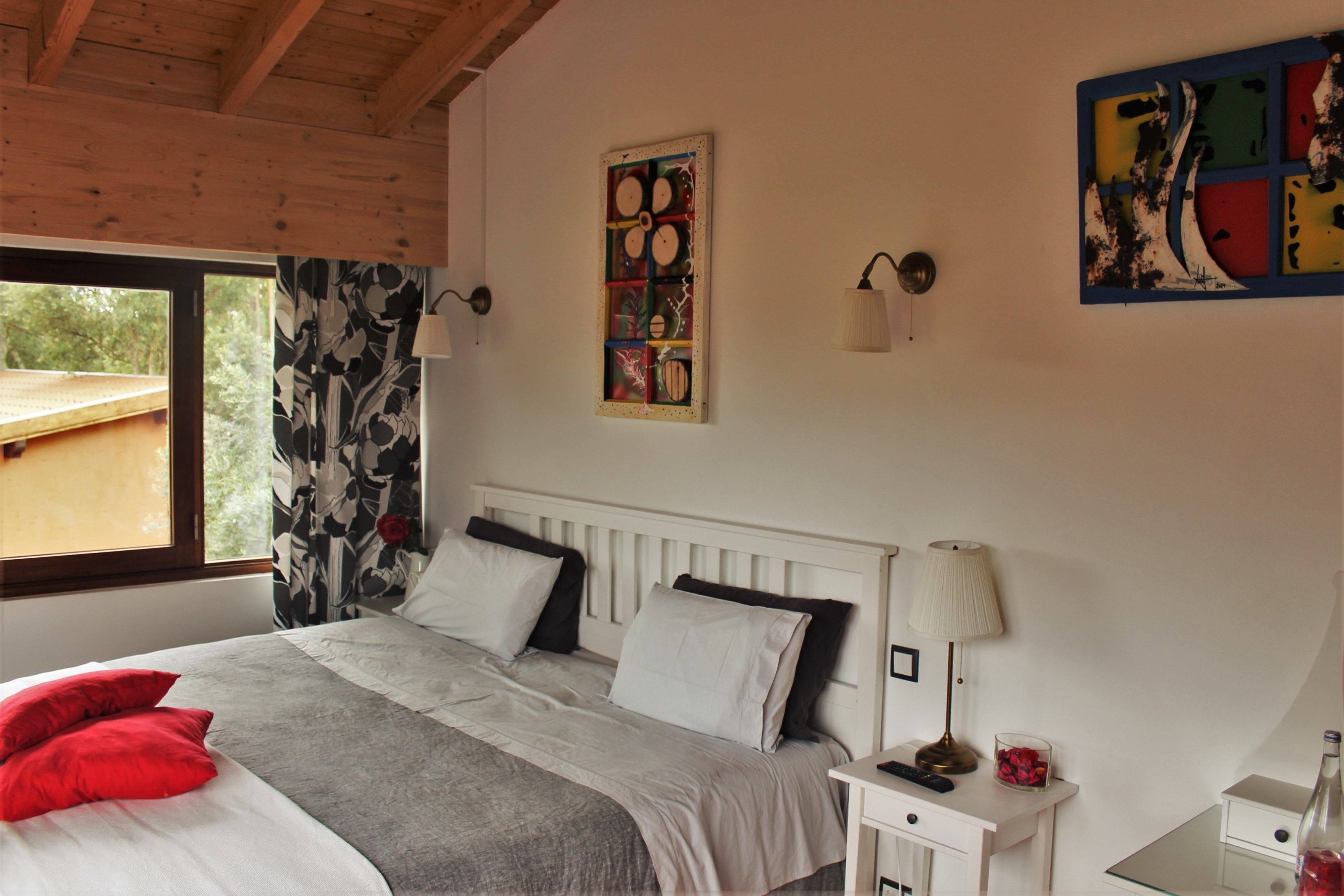 Une chambre à coucher comprenant un lit, une table de chevet, une lampe et une œuvre d’art murale.