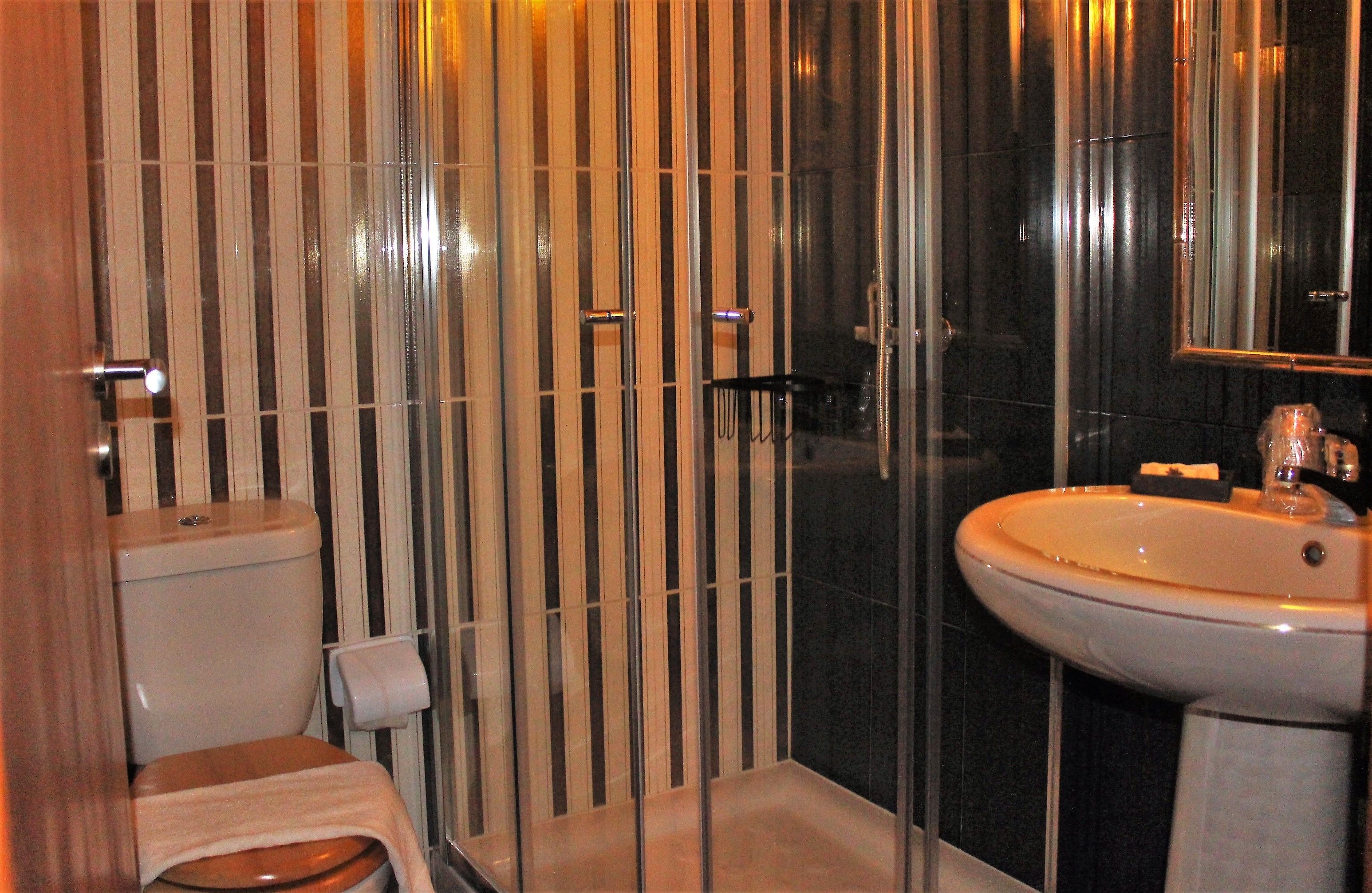 Un baño moderno con inodoro, lavamanos y zona de ducha.