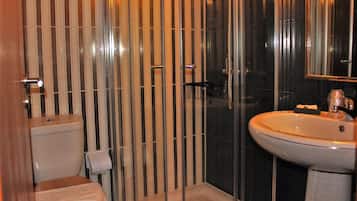 Un baño moderno con inodoro, lavamanos y zona de ducha.