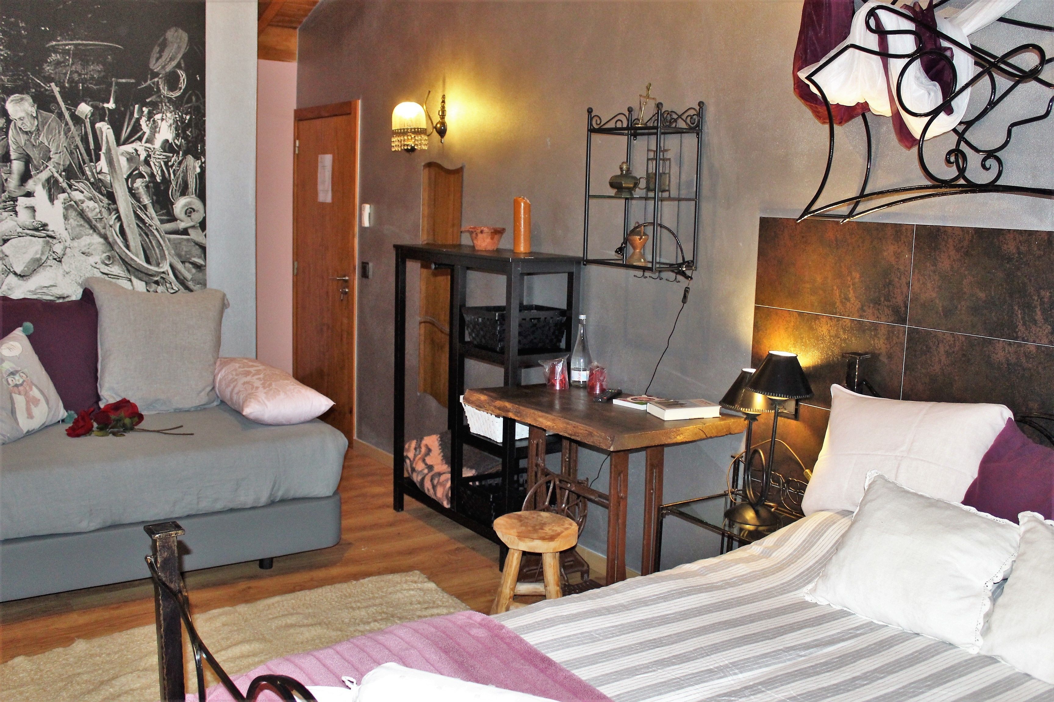 Una habitación acogedora con una cama, un sofá, una mesita y un estante en la pared.