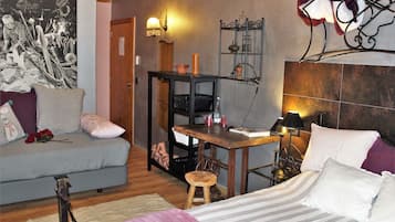 Una habitación acogedora con una cama, un sofá, una mesita y un estante en la pared.